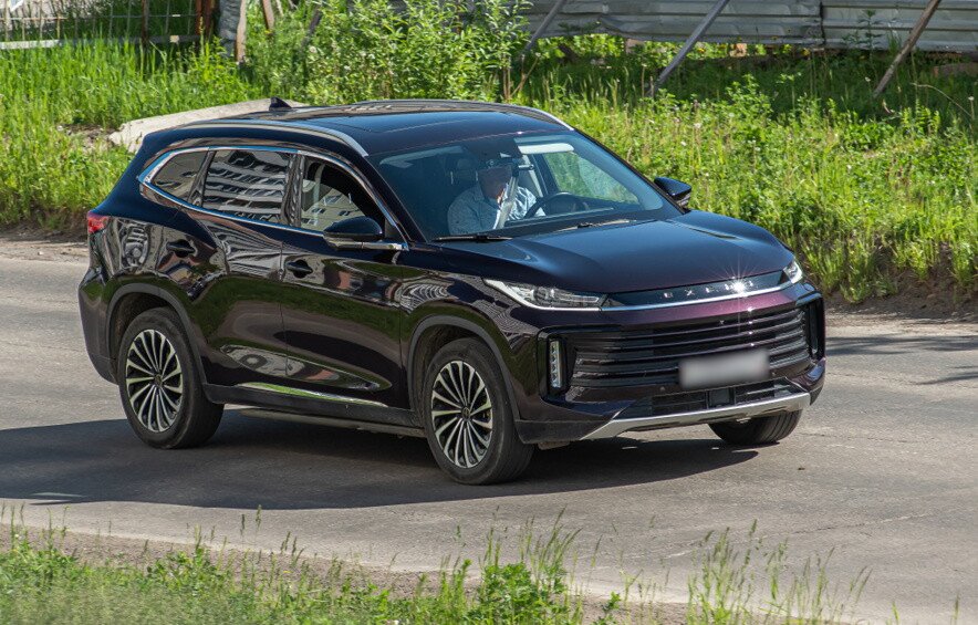 Темно-фиолетовый автомобиль Exeed TXL I едет по дороге