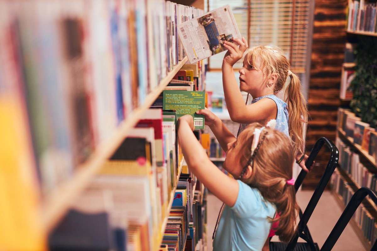 Две маленькие девочки выбирают книги на полке