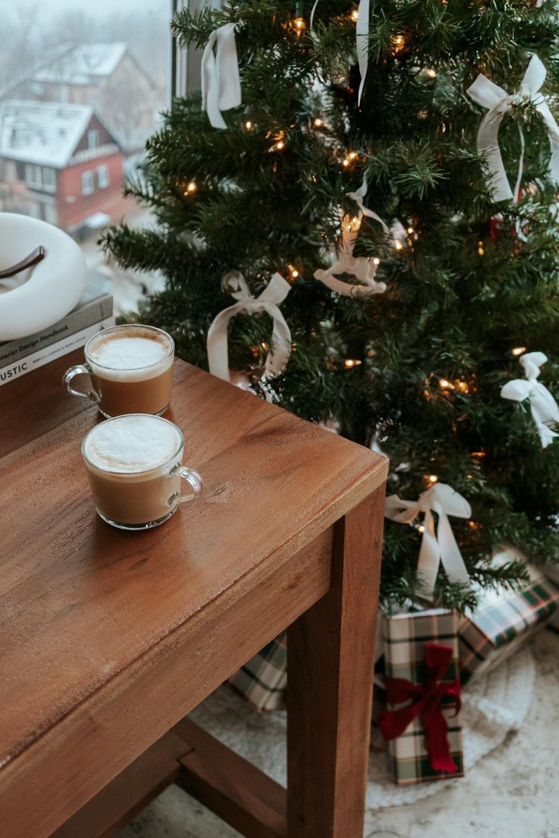 Стол с двумя кружками около нарядной ёлки и окна