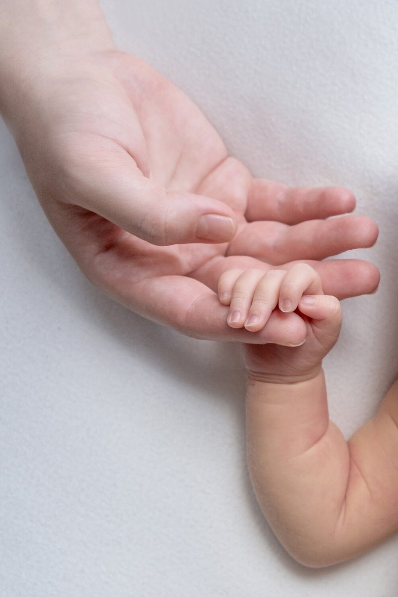 Рука мамы держит руку младенца