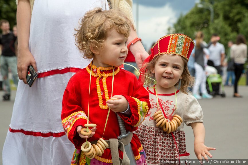 Маленькие мальчик и девочка в народных костюмах во время городского праздника