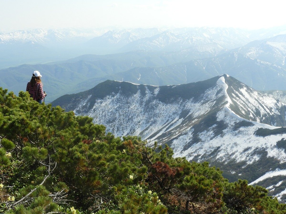 Туристка смотрит на заснеженные горные вершины