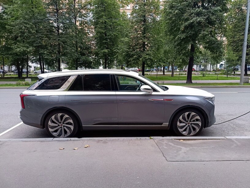 Серебристый электромобиль Hongqi E‑HS9 на парковке во время зарядки